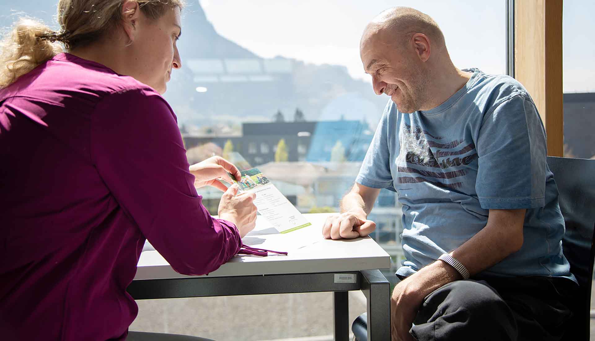 Assistenznehmer wird von einer Assistentin beim Lesen unterstützt