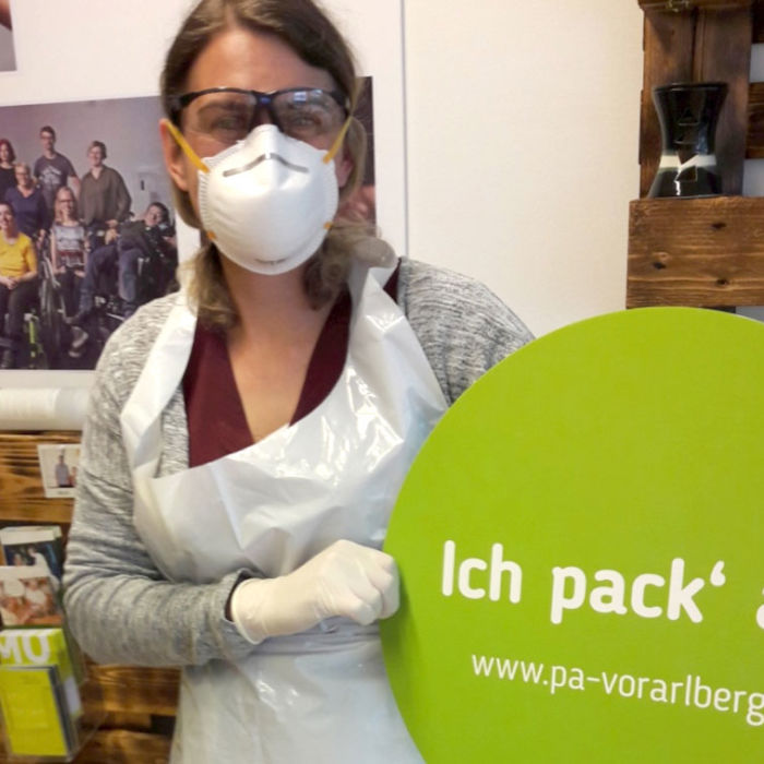 Frau mit einem Schild mit der Aussage „Ich pack' an!“