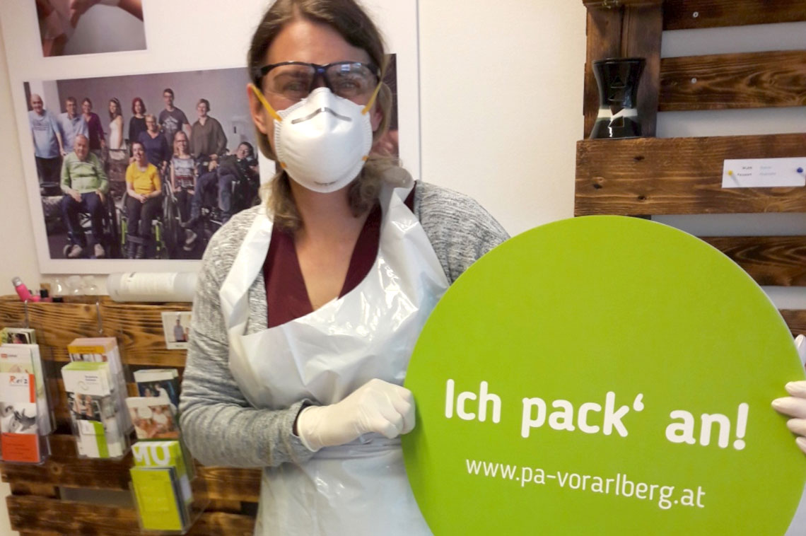 Frau mit einem Schild mit der Aussage „Ich pack' an!“